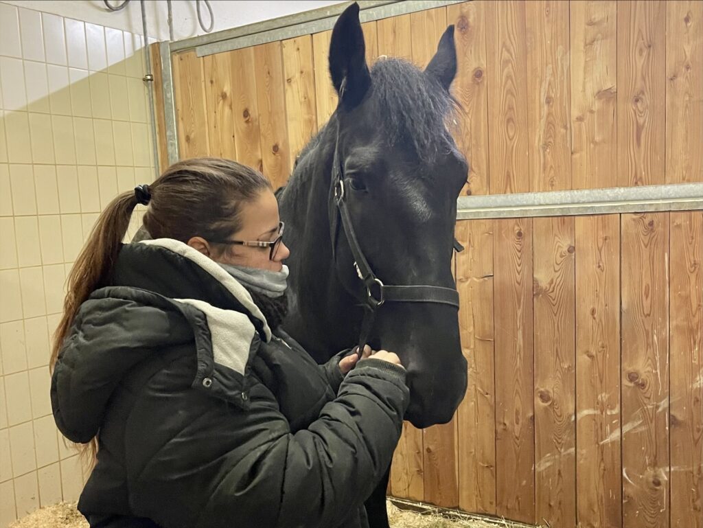 Eine junge Frau mit Pferd in einer Box auf der Klinik