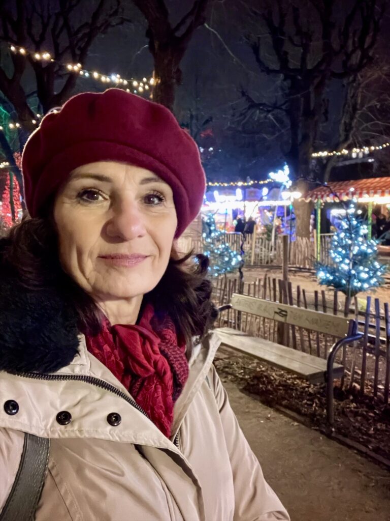 Eine Frau mit roter Kappe auf einem Weihnachtsmarkt im Freien