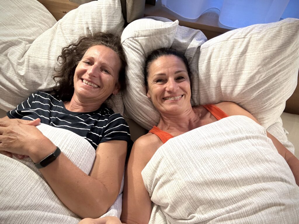 Zwei Frauen planen im Bett liegend die nächste Etappe