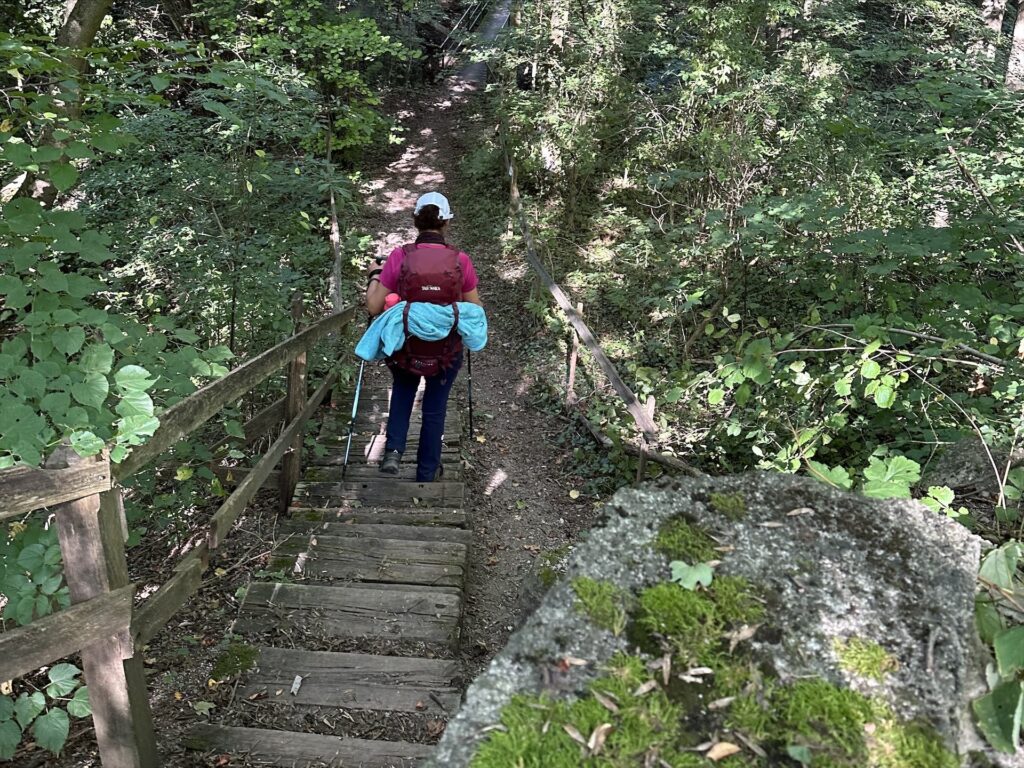 eine Wanderin steigt eine Treppe hinab zu einer Brücke