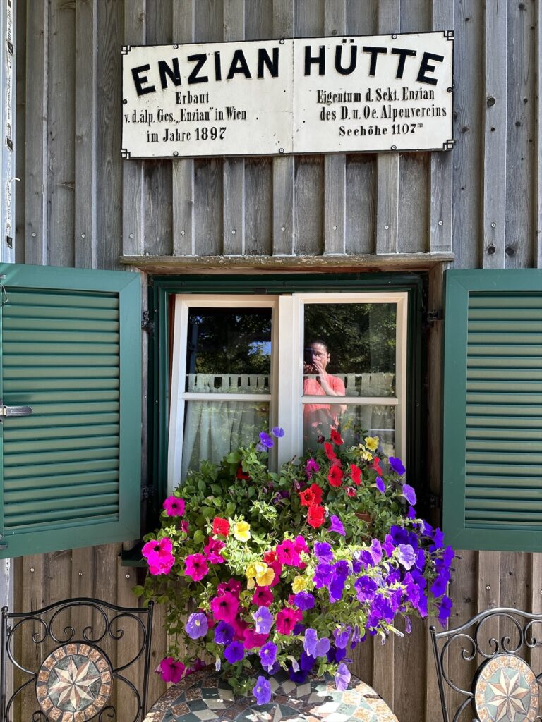 Enzianhütte mit prachtvollen Petunien am Fenster
