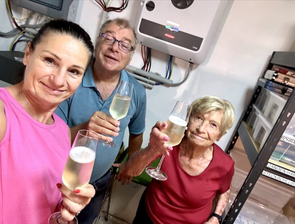 Drei Personen (2 Frauen, 1 Mann) feiern mit einem Glas Sekt im Heizraum den Projektabschluss.